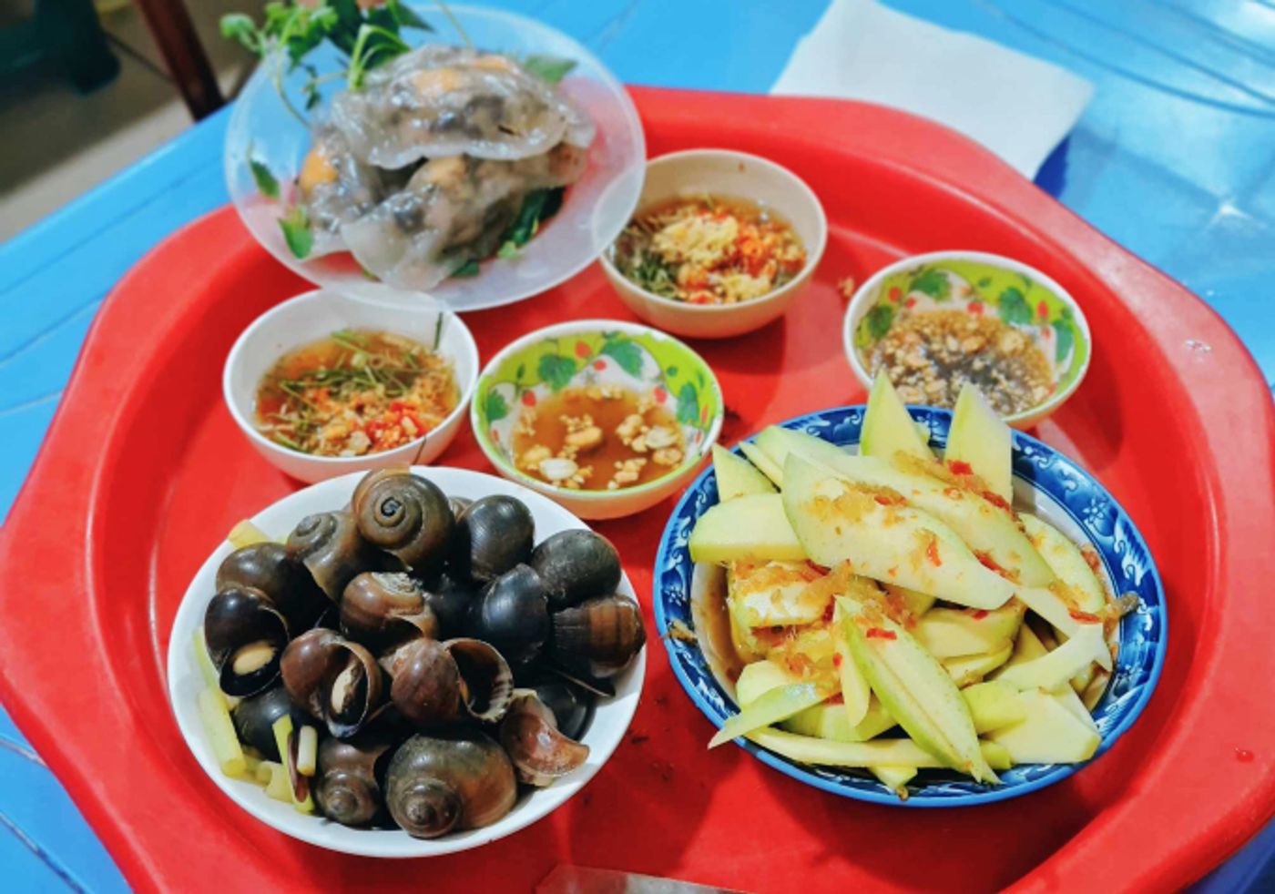 Common accompaniments to boiled snails often include stuffed tapioca dumplings (banh bot loc) and a side of mango mixed with salt and chili. Photo by VnExpress/Nguyen Chi